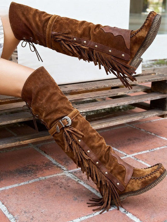 Botas altas planas de mujer con tachuelas y borlas por encima de la rodilla